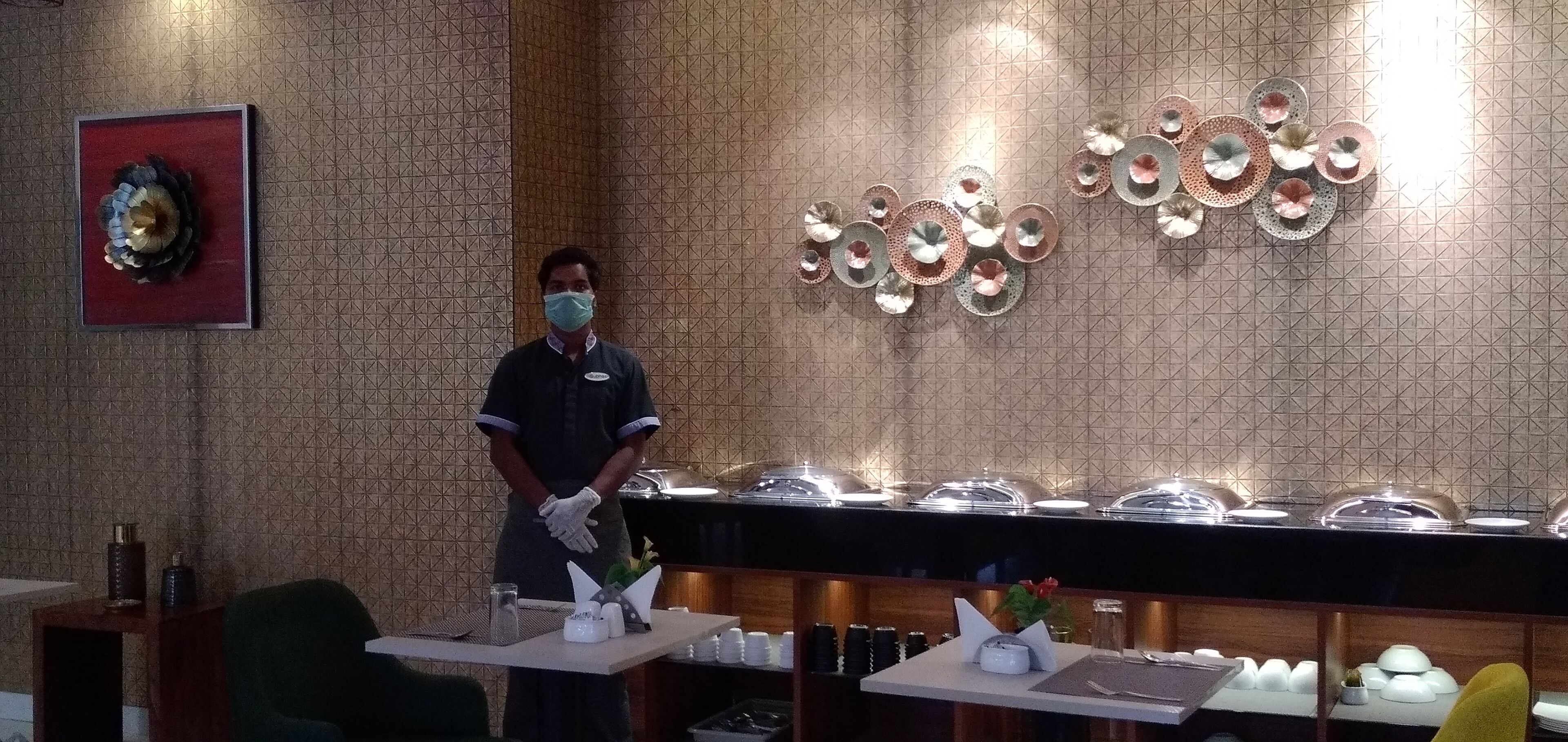 Zona de recepción de hotel con pared de diseño, un adorno mural y un mostrador de bufé con platos cubiertos.
