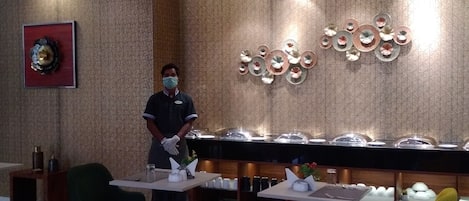 Zona de recepción de hotel con pared de diseño, un adorno mural y un mostrador de bufé con platos cubiertos.