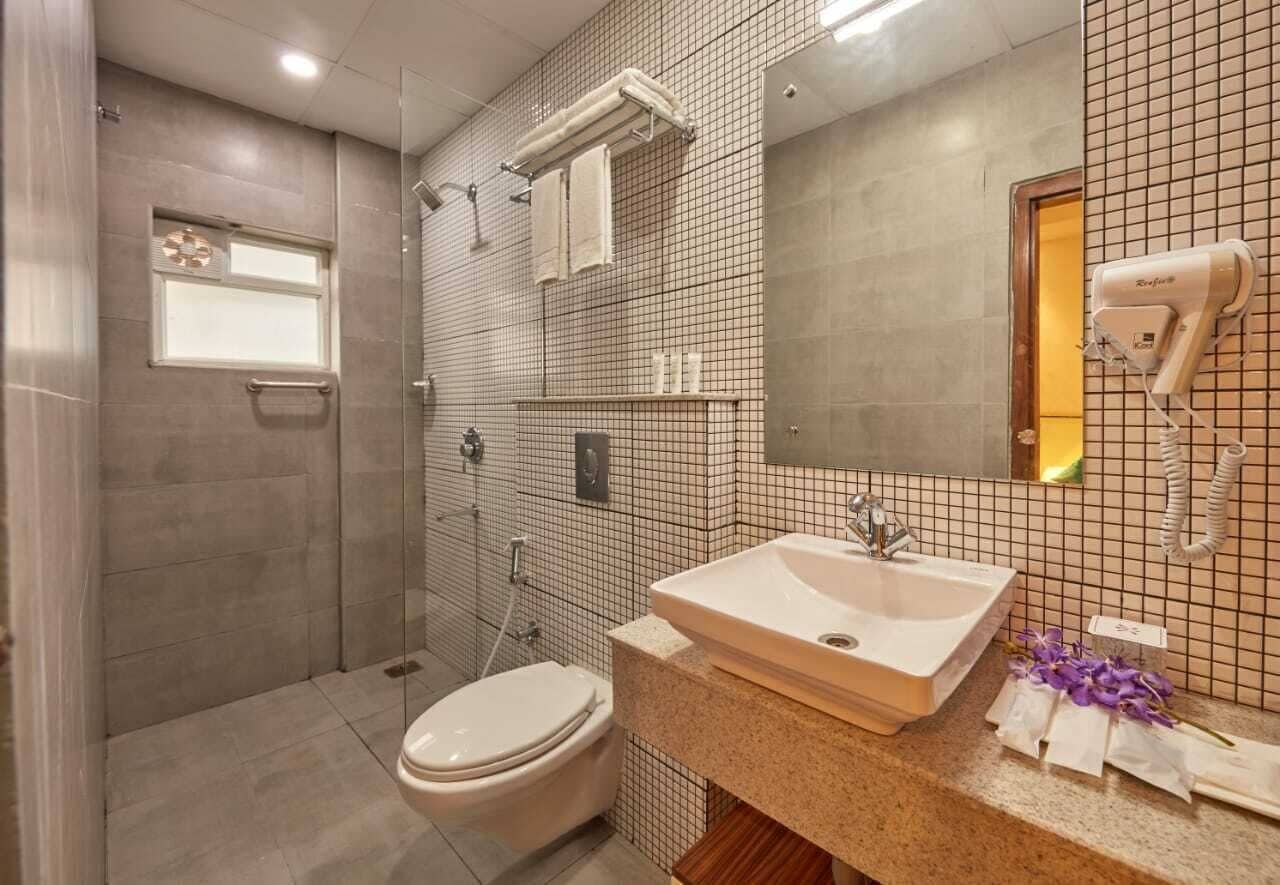 A modern bathroom with a glass shower enclosure, a white sink, and a large mirror.