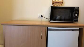 Una kitchenette con microondas y un refrigerador pequeño sobre una encimera de madera.