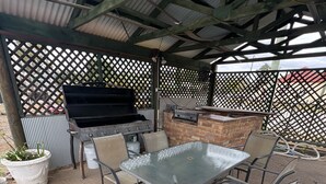 An outdoor patio with a grill, a table, and chairs. - Overlander Motor Lodge (Gunnedah)