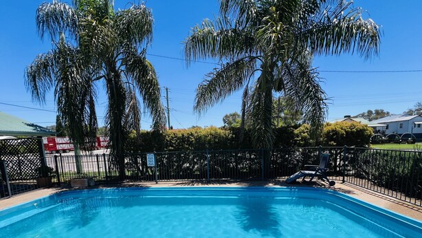 A rectangular swimming pool with clear blue water, surrounded by a black metal fence. - Overlander Motor Lodge (Gunnedah)