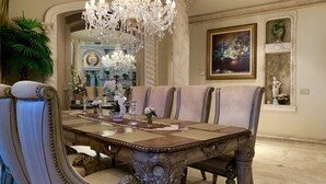 A formal dining room with a large ornate table, elegant chairs, and a chandelier.