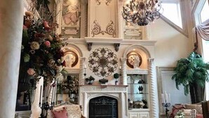 A grand room with a fireplace, ornate decorations, and a chandelier.