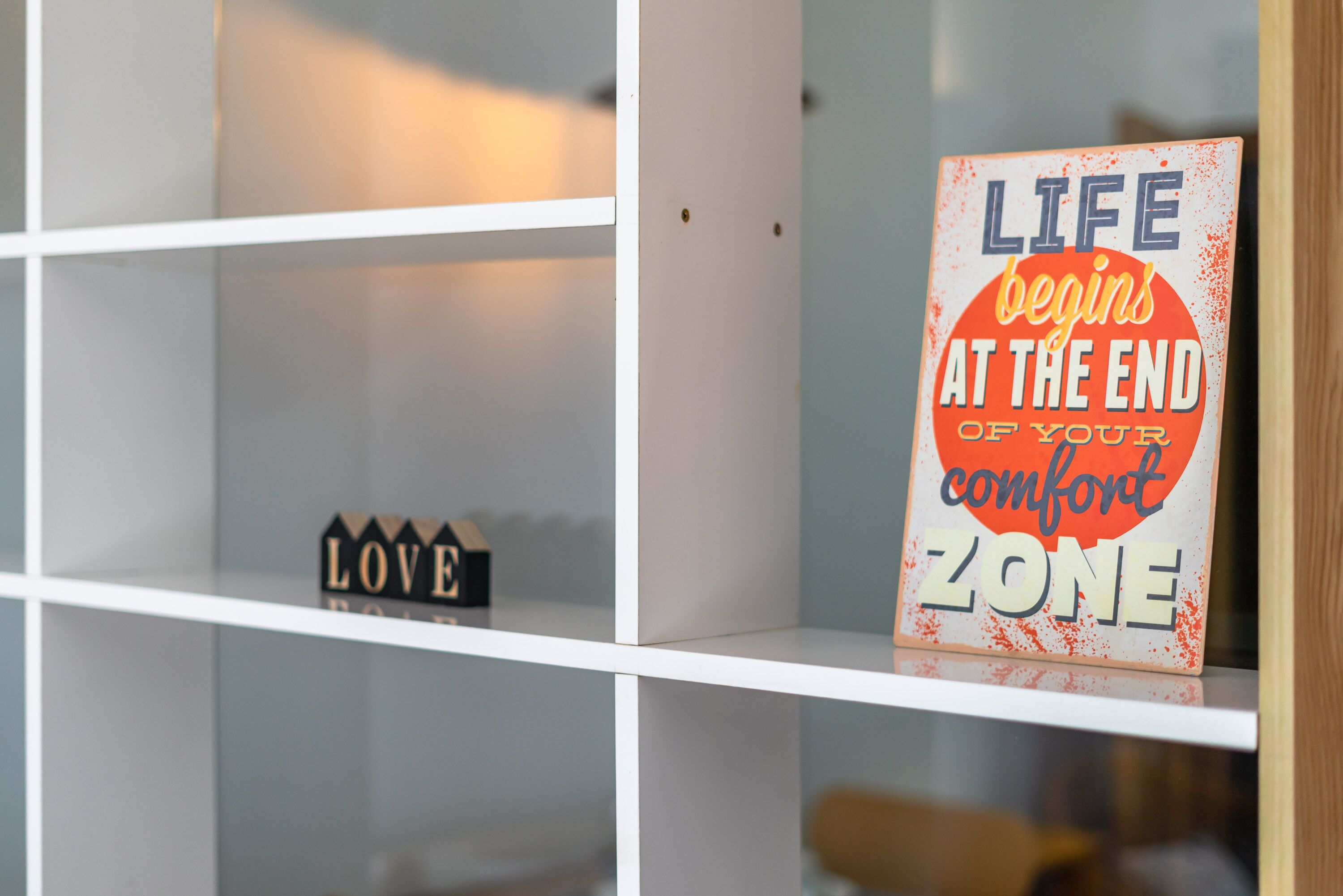 A shelf with a motivational sign and a small block with the word "LOVE".