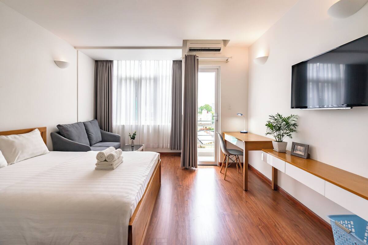 Ett hotellrum med en säng, ett skrivbord, en stol, en tv och en växt.