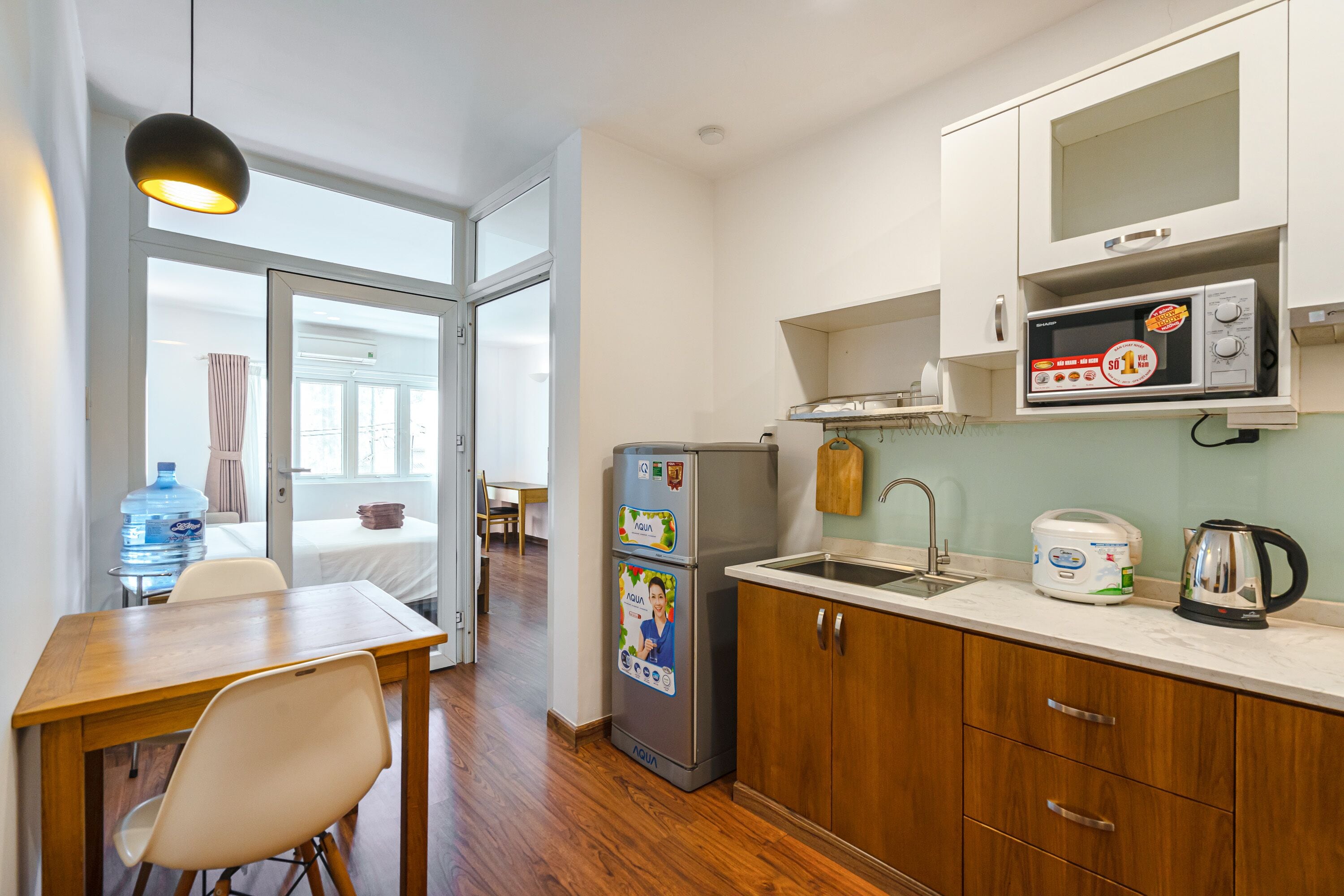 A compact kitchen with a refrigerator, microwave, and a water dispenser.