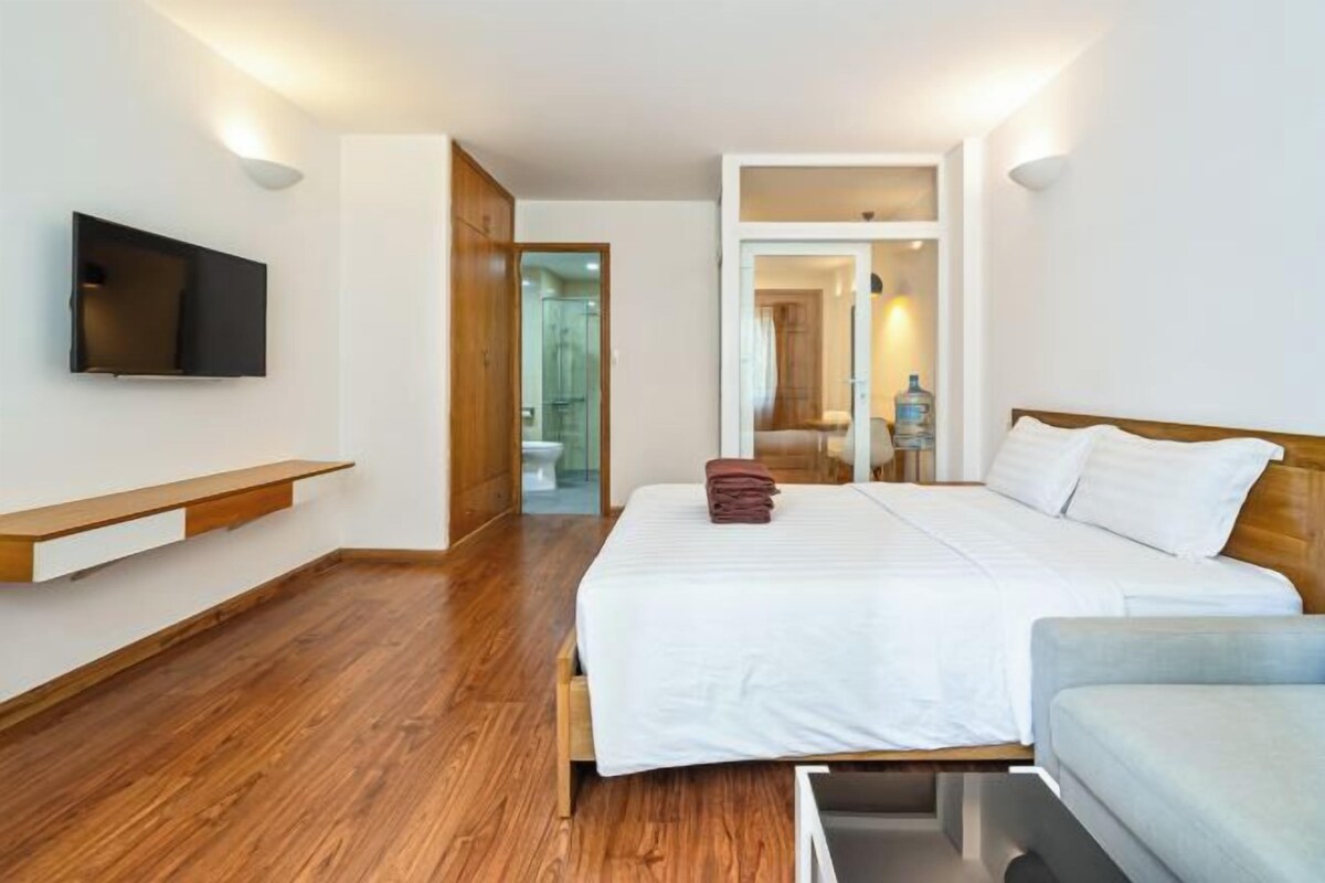 Una habitación de hotel moderna con una cama grande, un televisor montado en la pared y un banco de madera.