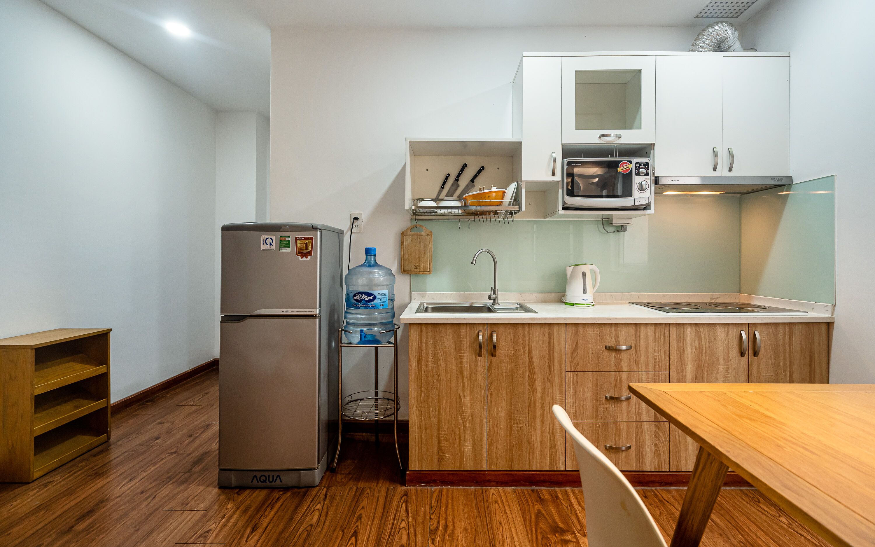 Una cocina compacta equipada con refrigerador, pileta, microondas y alacenas de madera.