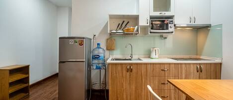 Una cocina compacta equipada con refrigerador, pileta, microondas y alacenas de madera.