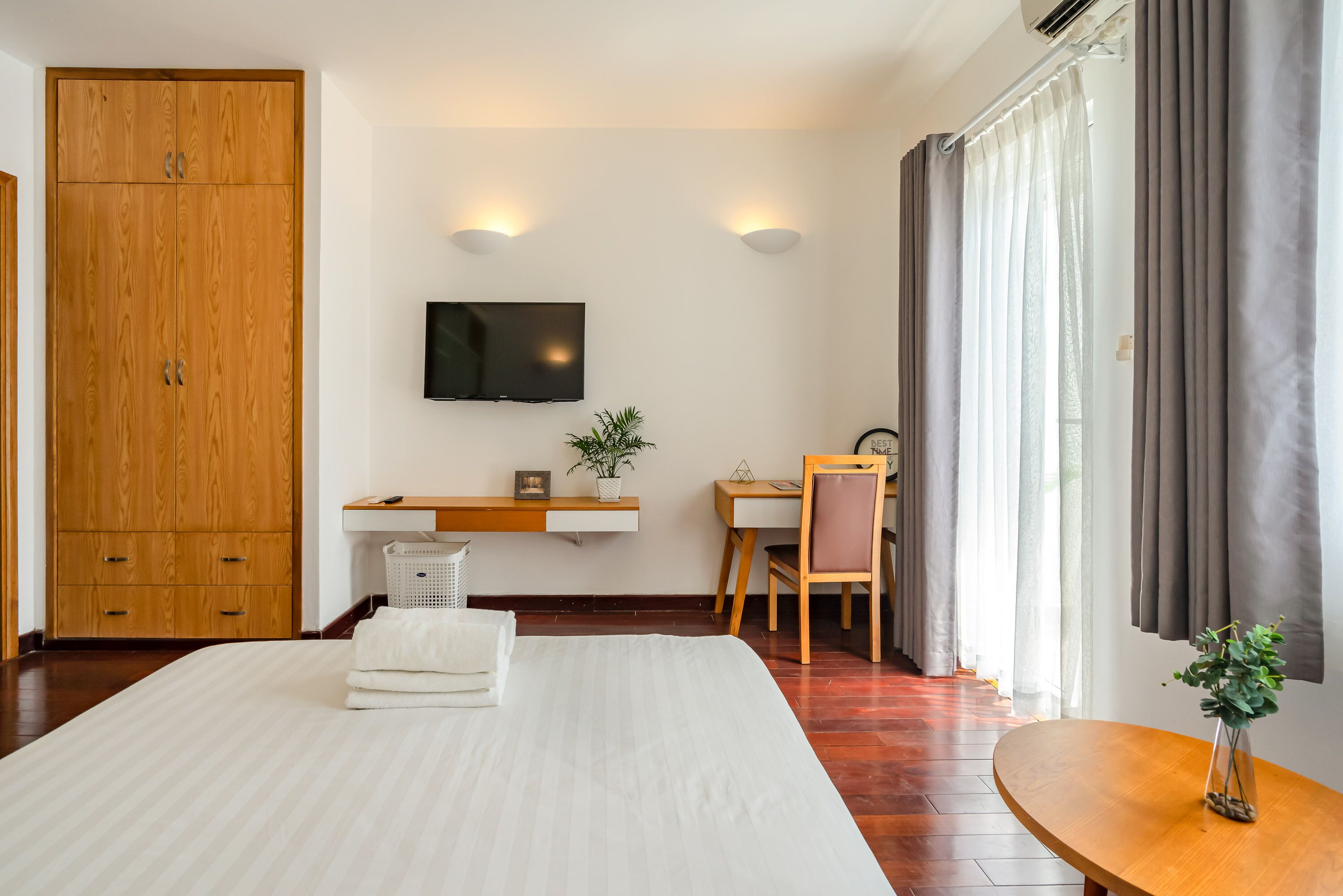 Ett hotellrum med en säng, ett skrivbord, en stol, en tv och en garderob.