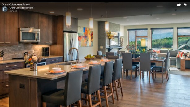 Une cuisine moderne dotée d’un îlot central, de meubles de couleur bois foncé et d’une grande fenêtre offrant une vue sur l’extérieur.