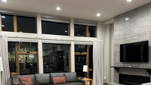 Un salon moderne avec un canapé d’angle, une table basse et un téléviseur fixé sur un mur en pierre.