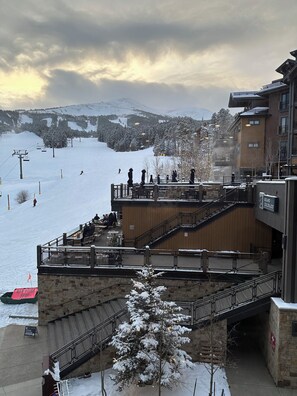 Estación de esquí con un paisaje cubierto de nieve, un telesilla y un edificio con un cartel que indica que está abierto.