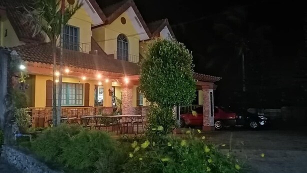 A two-story building with a dining area and outdoor seating, surrounded by greenery and a parked car. - Casa Marcosa Hotel (Tagaytay)
