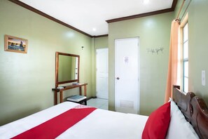 A bedroom with a bed, a desk, a mirror, a wardrobe, and a window with curtains. - Casa Marcosa Hotel (Tagaytay)