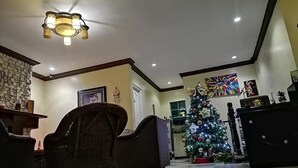 A living room with a Christmas tree, wicker chairs, a fireplace, and a ceiling light fixture. - Casa Marcosa Hotel (Tagaytay)