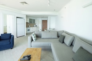 A modern living room with a grey sofa, a coffee table, and a blue armchair. - Mediterranean Sea Views | 1BR Apt by SeaNRent (Tel Aviv-Yafo)