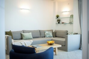 Una sala de estar moderna con un sofá gris, una mesa de centro de madera con un frutero y una silla azul.