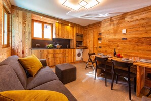 A cozy living area with a sofa, ottoman, and dining table set for four. - Marlies Ski in - Ski out 50m, Livigno, Italy (Livigno)
