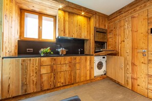 A kitchen with wooden paneling, a black countertop, a sink, a stove, and a washing machine.
