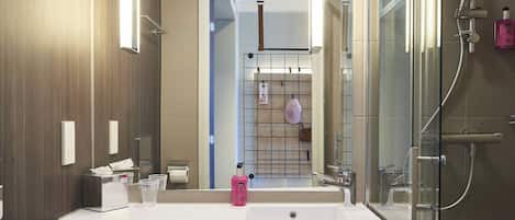 Une salle de bain moderne avec un grand lavabo, une douche à parois de verre et un miroir.