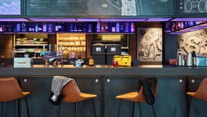 Un espace bar avec un panneau néon, des étagères remplies de bouteilles et des tabourets de bar.