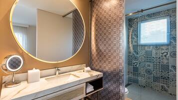 Un baño con un espejo redondo, un lavabo y una zona de ducha.