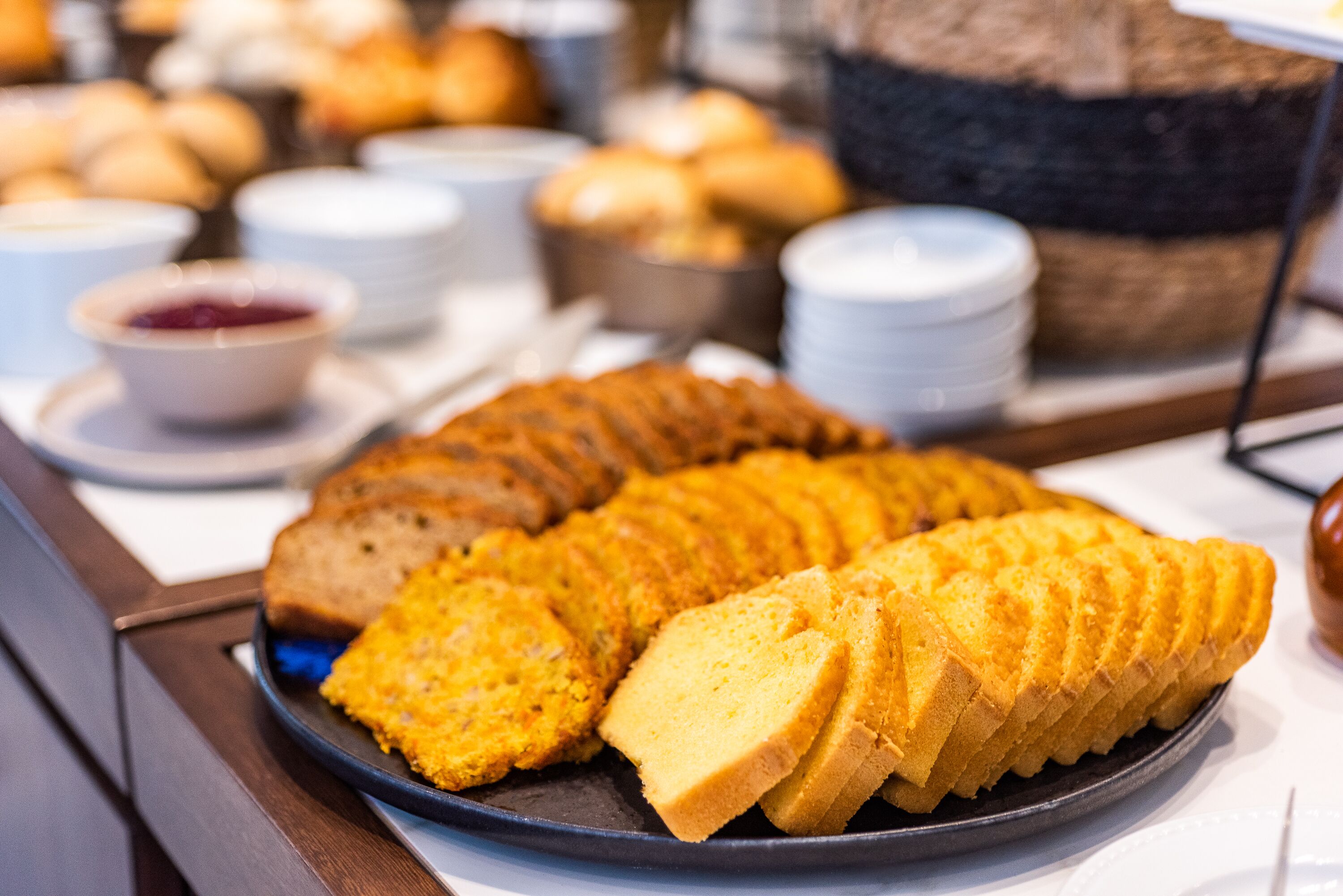 A buffet with a variety of baked goods including a large bundt cake and several types of bread.