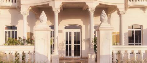 Un imponente acceso con un vano central flanqueado por columnas y una barandilla decorativa.