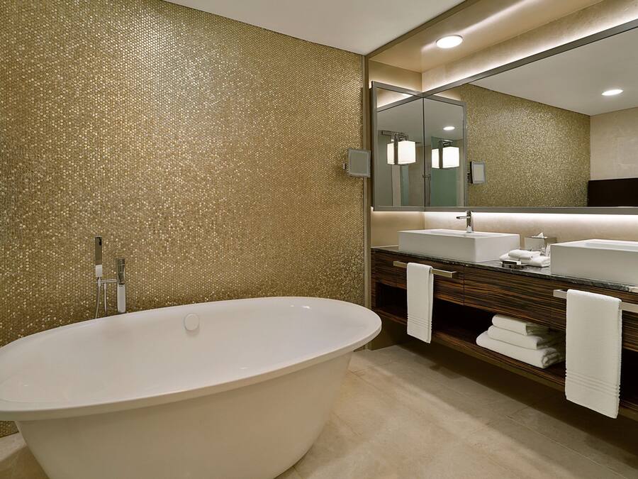 A modern bathroom with a freestanding bathtub, a large mirror, and a vanity with a sink and towel rack.