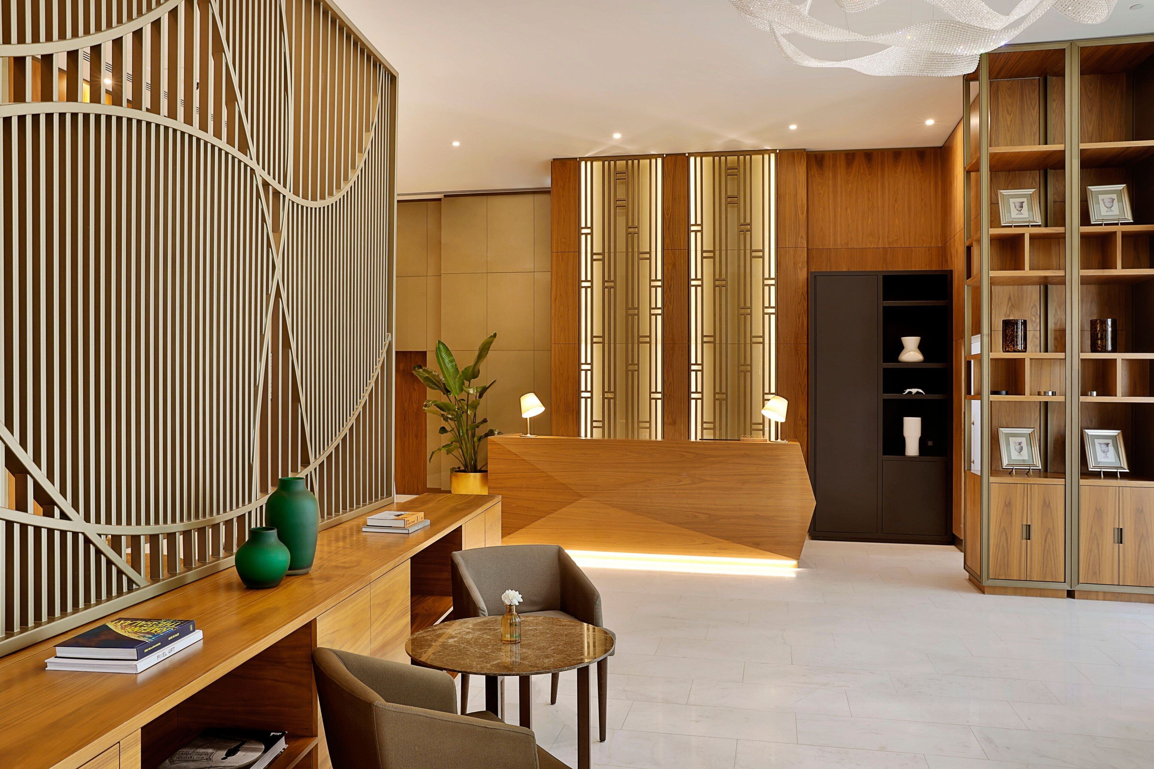 Un espace d’accueil moderne avec un comptoir de réception en bois, des sièges et une plante décorative.