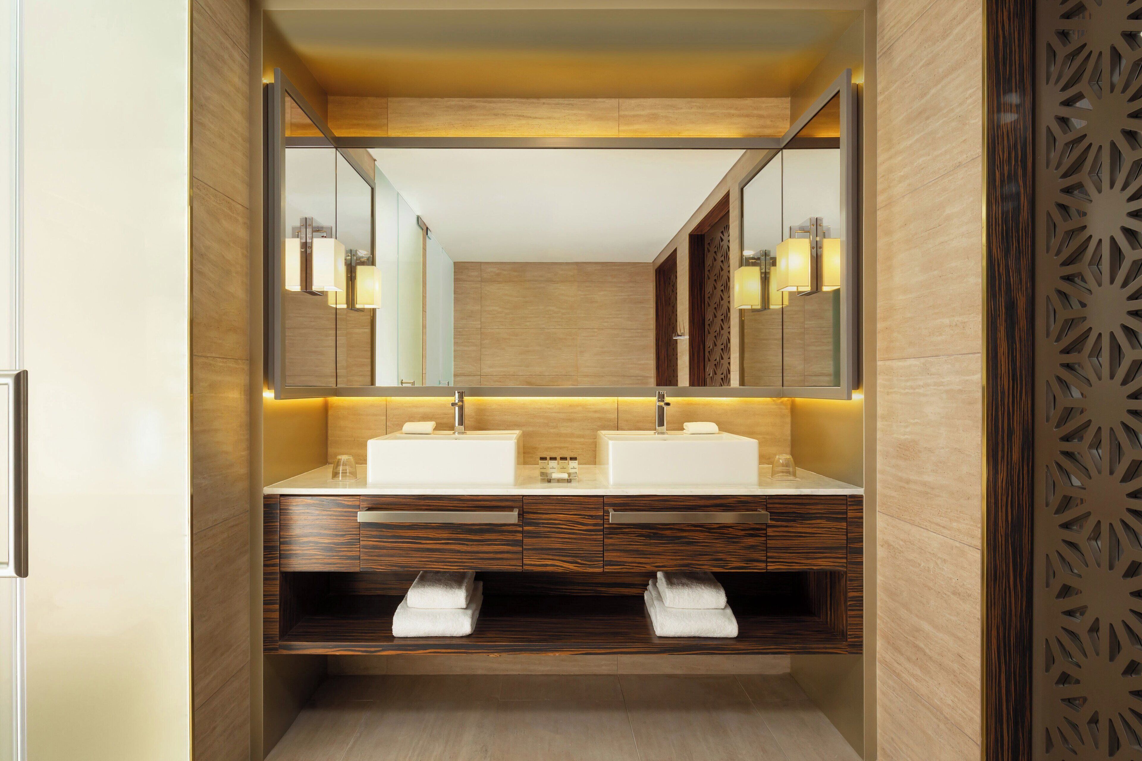 Un baño moderno con dos lavamanos, muebles de madera y un espejo grande.