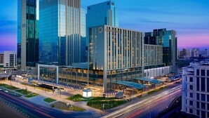 A modern hotel with a glass facade, a prominent Sheraton sign, and a well-lit entrance area. - Sheraton Astana Hotel  (Astana)