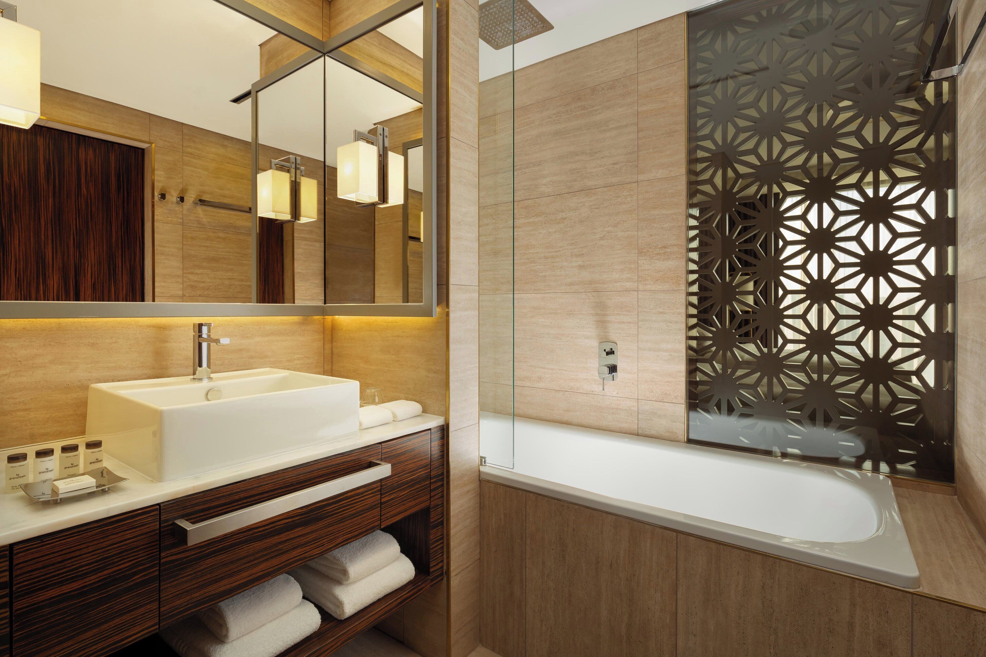 A modern bathroom with a large mirror, a sink, and a shower area.