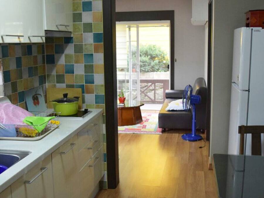 Una cocina con un lavamanos, una estufa y un refrigerador. Hay una ventana con vista al exterior.