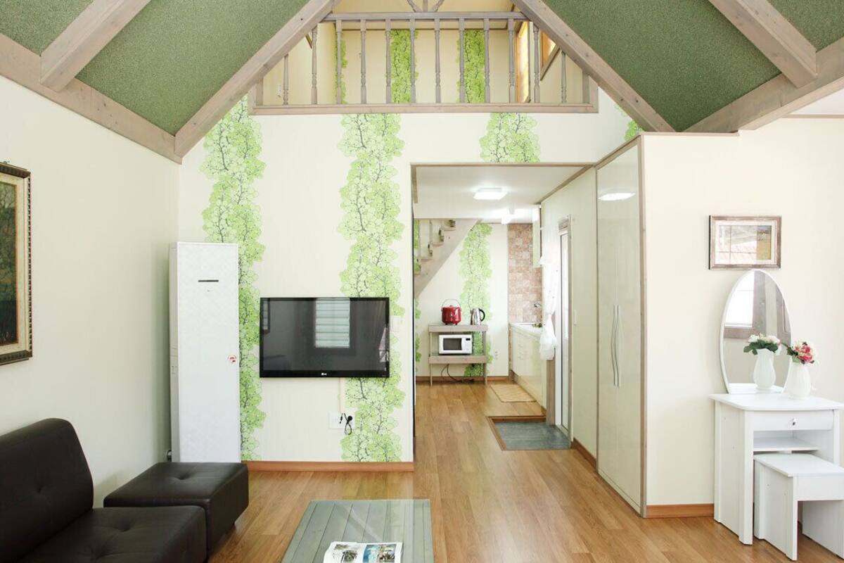 Ein Wohnzimmer mit einer Couch, einem Flachbildfernseher und einem Gemälde an der Wand.