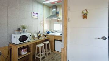 Una cocina compacta con microondas, pileta y taburetes.