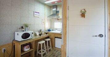 Una cocina compacta con microondas, pileta y taburetes.