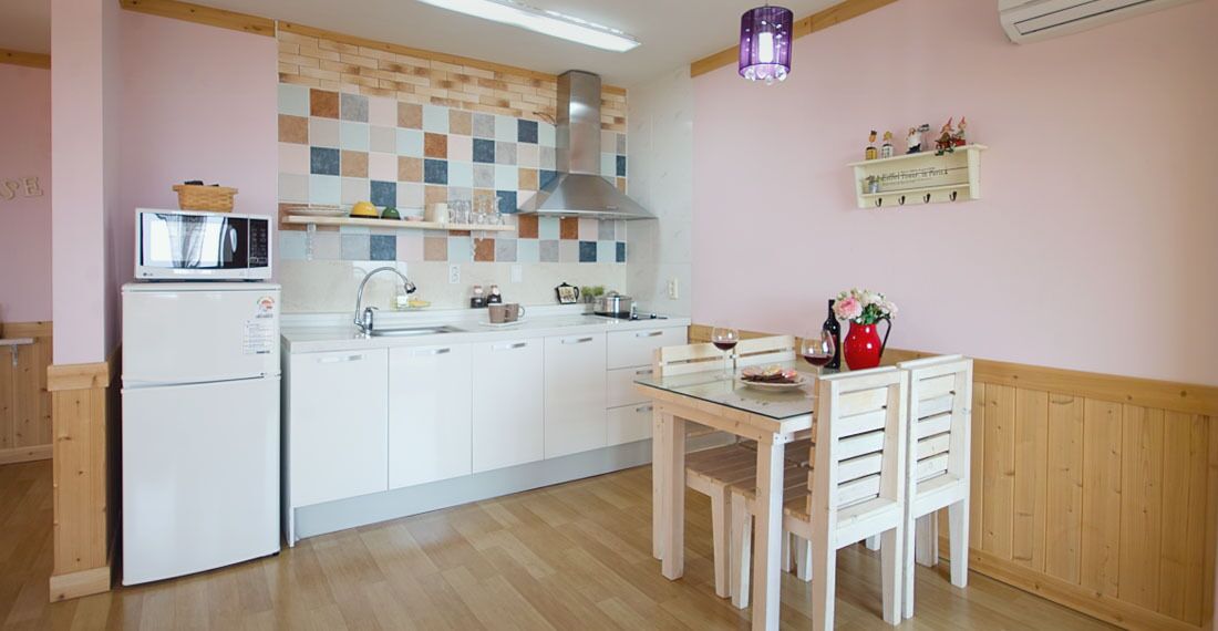 A kitchen with white cabinets, a microwave, a stove, and a dining table with chairs.