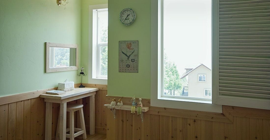 Une pièce avec un bureau en bois, un miroir, une horloge et un calendrier accroché au mur.