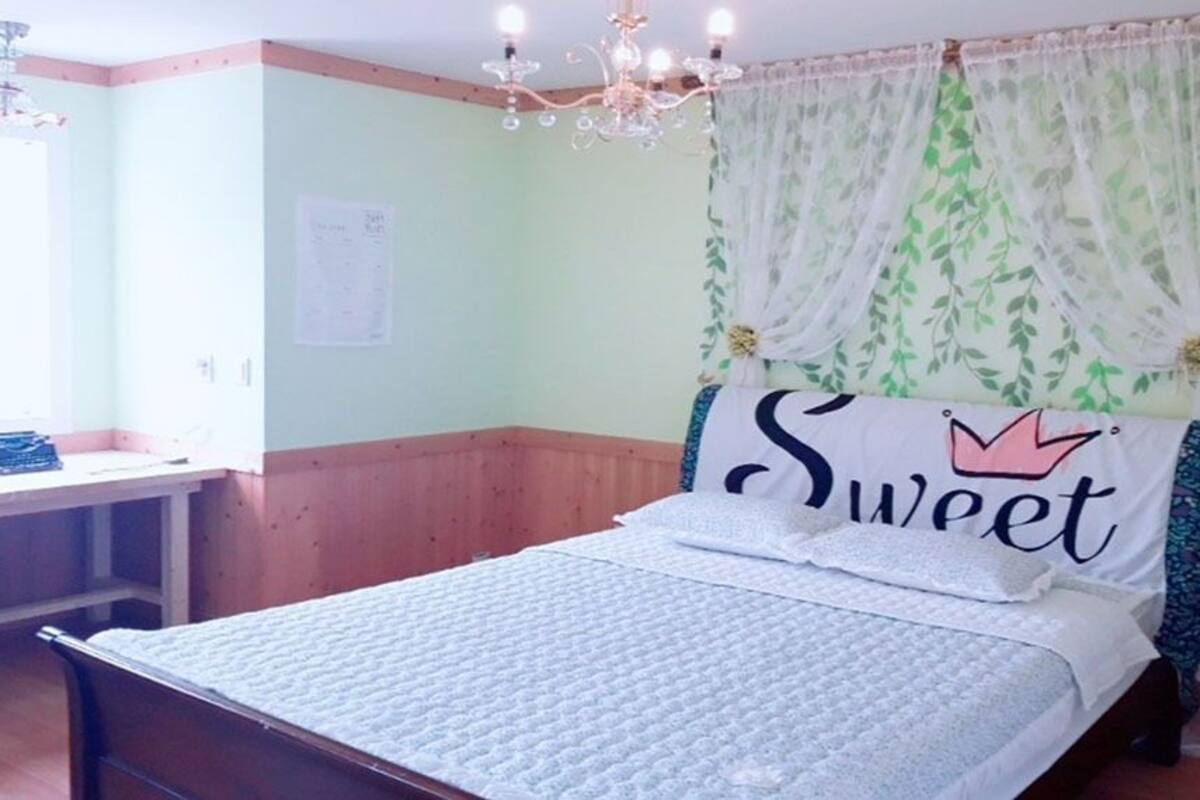 Une chambre à coucher avec un lit, une table de chevet, un lustre et une fenêtre avec des rideaux.