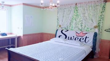 A bedroom with a bed, a bedside table, a chandelier, and a window with curtains.
