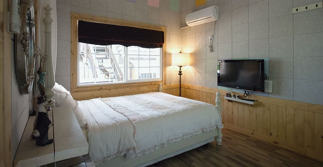 Une chambre à coucher avec un lit, une télévision, une fenêtre donnant sur un beau paysage et une lampe.