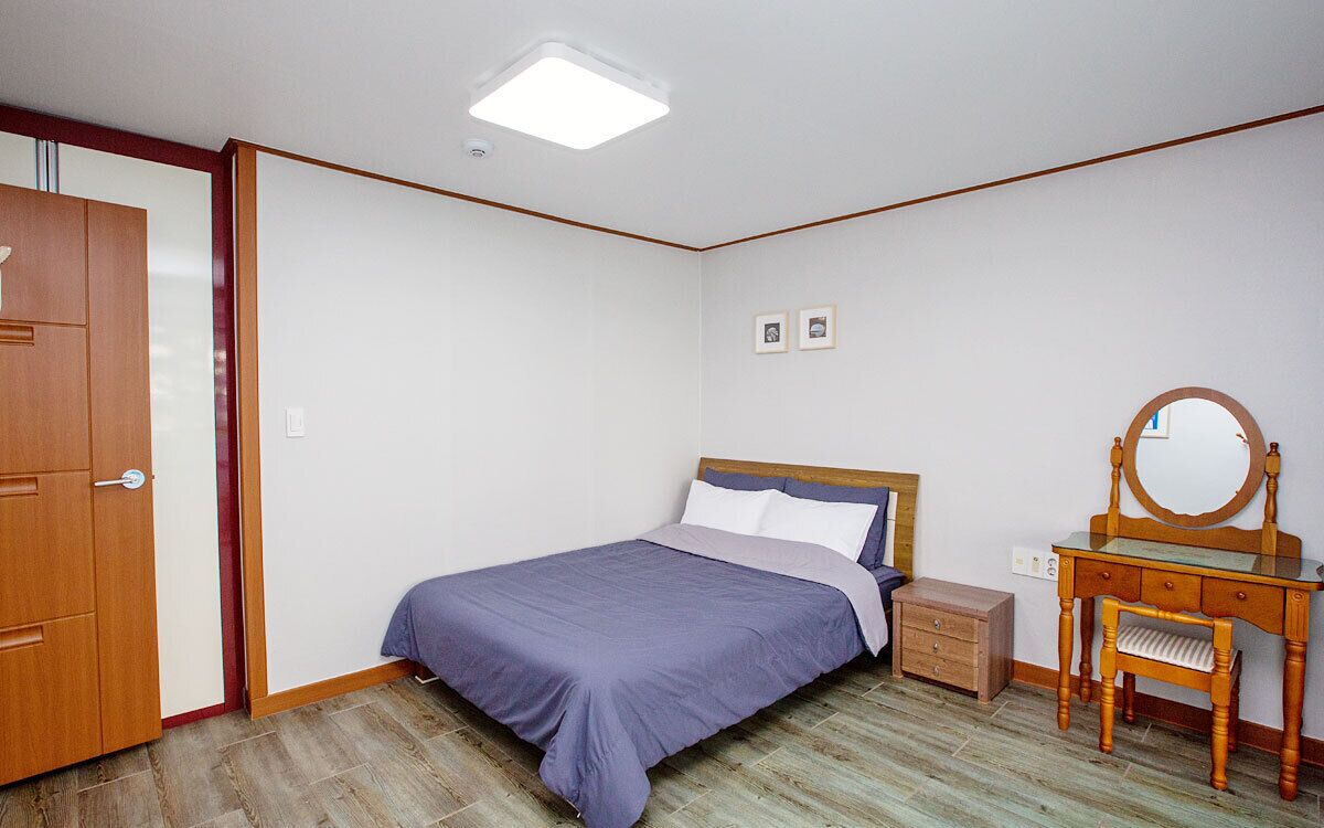 Ein Schlafzimmer mit einem Bett, einer Holzkommode, einem Spiegel und einem kleinen Nachttisch.