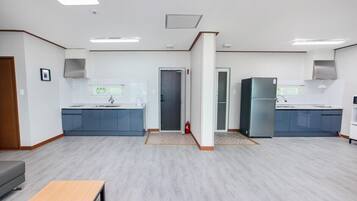 A modern kitchen with grey cabinets, a wooden bench, and a fire extinguisher.