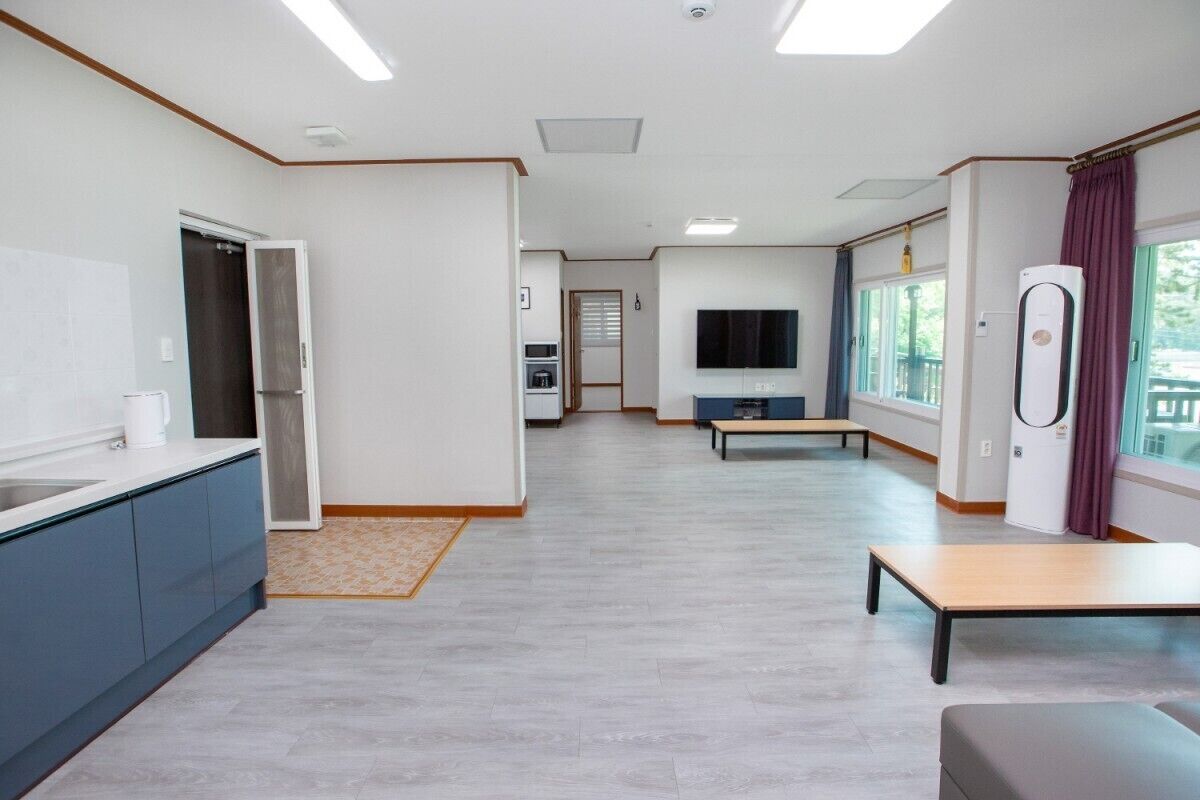 A modern kitchen with a built-in oven, a dining area with a bench, and a large window with curtains.