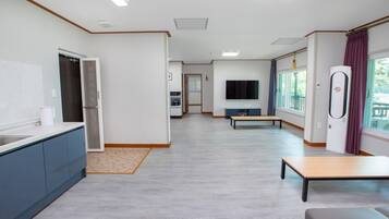 A modern kitchen with a built-in oven, a dining area with a bench, and a large window with curtains.