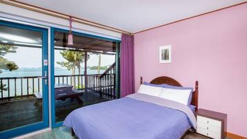 A bedroom with a bed, a nightstand, and a view of a balcony with a table and chairs.