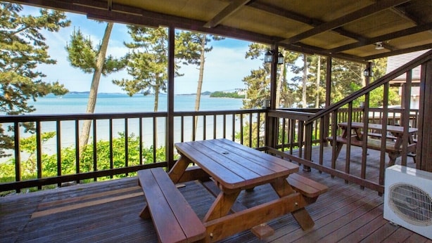 A wooden deck with picnic tables overlooking a body of water and trees. - Haesol Maru Pension Taean (Taean)